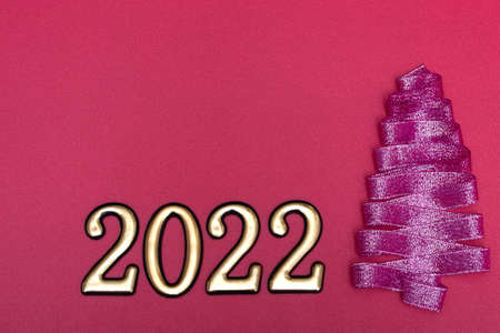 Christmas concept. Purple Christmas tree made from ribbons and gold numbers on a pink background...