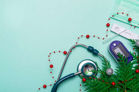 Christmas greeting card. stethoscope, pulse oximeter, rapid test and Christmas decorations on green background, Medical concept. Copy space, flat lay.の写真素材