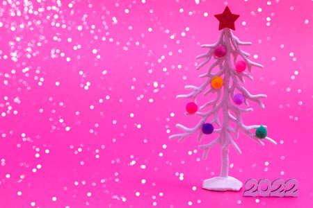 Christmas card. Against the background of Christmas lights, a white Christmas tree in multi-colored fur toys with the numbers 2022. Close-up copy spaceの写真素材