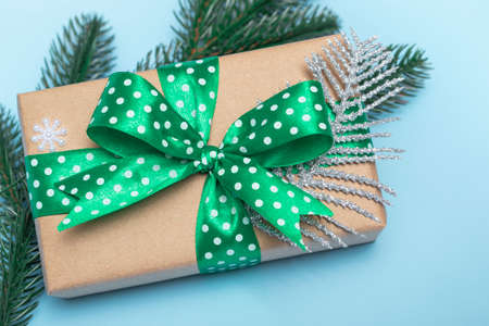 Merry Christmas and Happy New Year. Gift with a green ribbon with polka dots and ornaments on a blue background. Holiday card with copy space close upの写真素材