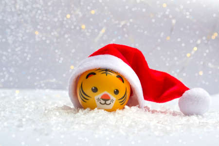 The symbol of the new year is a tiger in a Santa hat on the snow against a background of bokeh lights. Close up of new year conceptの写真素材