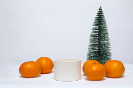 Close-up of a podium on a white background, decorated with a Christmas tree and tangerines. Happy New Year and Merry Christmas.の写真素材