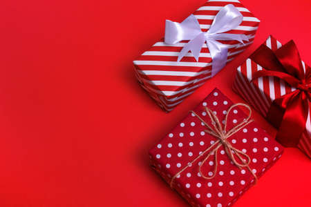 Top view of white color gift with red stripes and white polka dots on red background with copy space