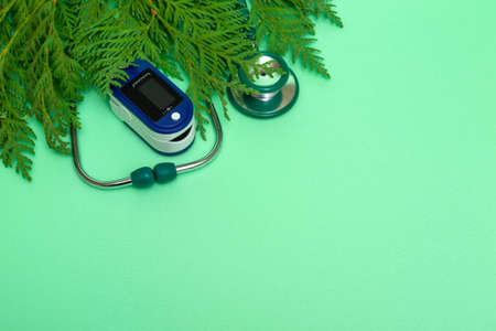 Medical concept: celebrating Christmas in healthcare. Top view of a flat lay close-up of a stethoscope, pulse oximeter with fir branches on a green background.copy spaceの写真素材