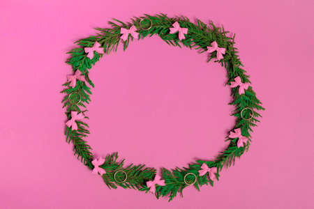 Christmas wreath of fir branches and decorations on a pink background. Flat lay, top view, copy space. Christmas compositionの写真素材