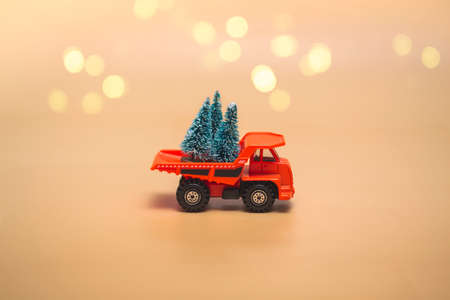 Orange truck with Christmas trees on a beige background with lights. Holidays concept. Close up,  copy space.の写真素材