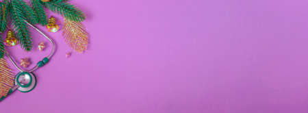 Top view of flat Christmas decorations and stethoscope on purple background. Concept for medical announcement, banner. copy spaceの写真素材