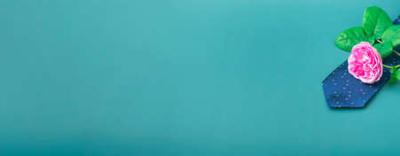 Blue tie with a tea rose on a turquoise background. Holiday gifts close up with copy space. Banner