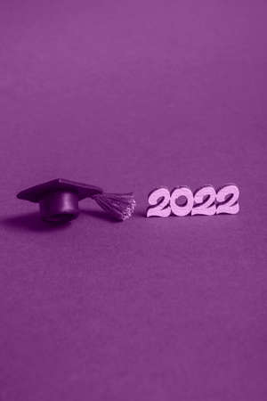 Graduation cap  and numbers 2022 on violet background, close up with copy space. Medical education...