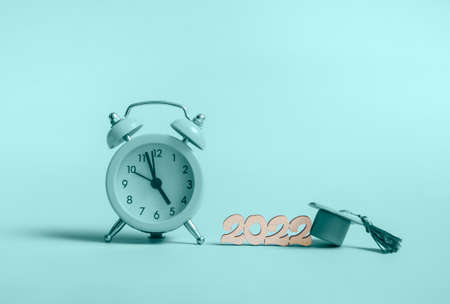 Yellow alarm clock with graduation cap on blue background close up with copy spaceの写真素材