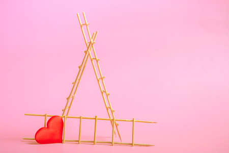 Wooden ladder with red hearts on a pink background. Postcard or invitation template. Close upの写真素材