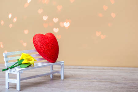 Red heart with a bouquet of yellow lilies on a white bench against a background of bokeh. Love concept, closeup with copy space.の写真素材
