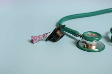 Graduation cap with stethoscope and numbers 2022 on blue background, close up with copy space. Medical education concept.の写真素材