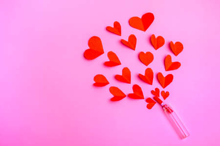 Red paper hearts flying out of a bottle. Valentine on pink background with copy spaceの写真素材