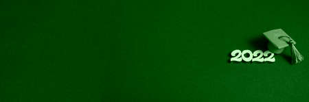 Graduation cap and numbers 2022 on green background, close up with copy space. Medical education...