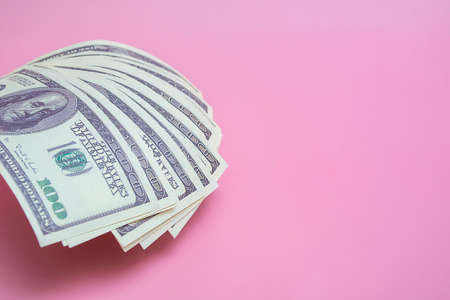 One hundred dollar bills on a pink background, close up with copy spaceの写真素材