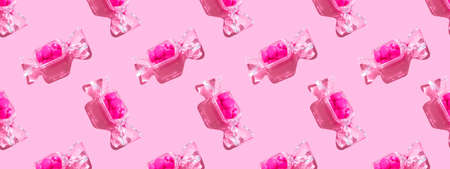 Transparent candy shaped box with sweet heart lollipops with hard shadow on pink background with...