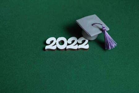 Graduation cap  and numbers 2022 on green background, close up with copy space. Medical education...