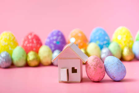 Stylish Easter eggs and a house on a pink background. Family holiday concept. Greeting card...