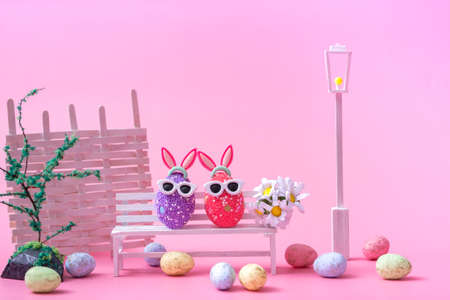 Close up on a pink background multi-colored eggs on a white bench. Easter background, postcard, banner.の写真素材