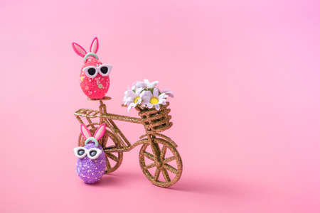 Easter composition on a pink background, an egg with rabbit ears and sunglasses, close up with copy...