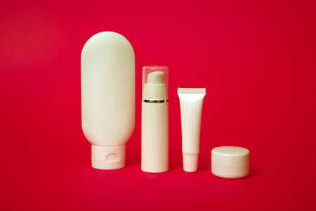 Close up of white tubes for various cosmetics on a red background. With copy space.の写真素材