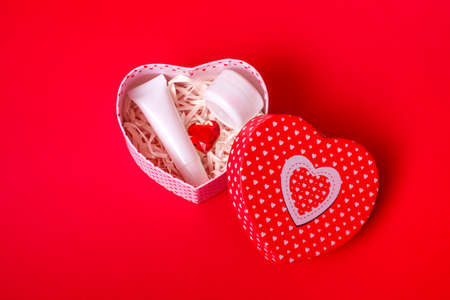 On a red background, a gift box with cosmetics. The concept of valentines day, mothers day, sale. With copy space, closeupの写真素材
