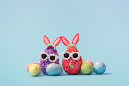 Colorful Easter egg with bunny ears and sunglasses on a blue background. Sale banner, mockup...