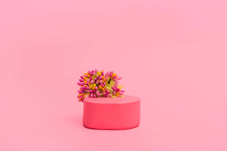 Pink podium for cosmetics or products with flowers and hearts on a pink background. Holiday card, close up copy spaceの写真素材