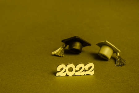 Graduation cap and numbers 2022 on gold background, close up with copy space. Medical education concept.の写真素材