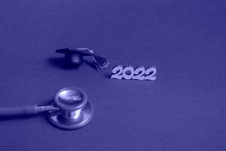 Graduation cap with stethoscope and numbers 2022 on very peri background, close up with copy space....