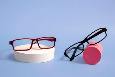 Classic glasses on a natural stone podium on a blue background. Optics. Close up with copy spaceの写真素材