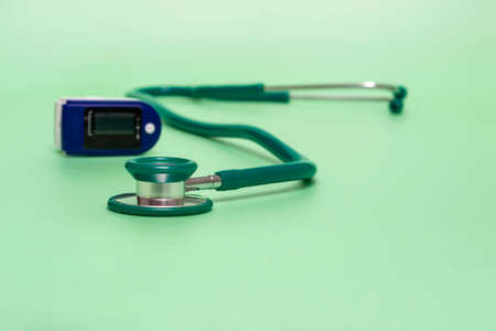 Medical concept. pulse oximeter and stethoscope on a green background. Prevention and treatment of pneumonia, influenza, isolation. oxygen meter. Bannerの写真素材
