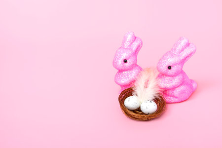 Easter bunnies and a nest with eggs on a pink background. Holiday concept. Close up copy space