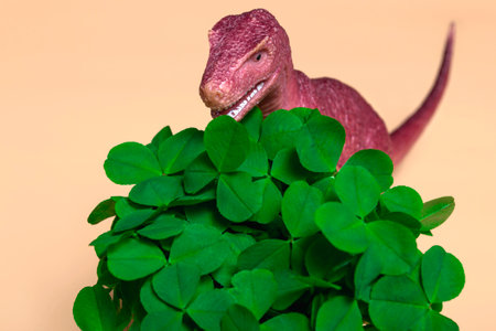St. Patrick's Day happy dinosaur, a bouquet of clover in a bucket and gold coins on a beige background. Close up copy spaceの写真素材