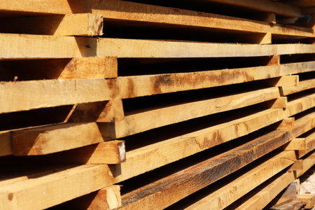 Wooden boards close up. Lots of boards stacked on top of each other in a warehouse. Perspective angle of wooden boards close-up in a lumber warehouse. Background from boards.の写真素材