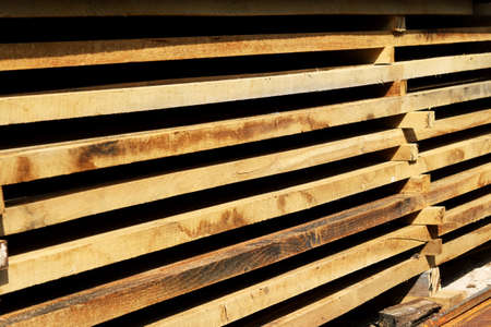 Wooden boards close up. Lots of boards stacked on top of each other in a warehouse. Perspective angle of wooden boards close-up in a lumber warehouse. Background from boards.の写真素材