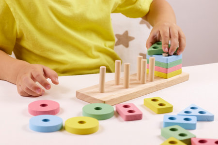 The child plays with colorful toy blocks. eco wooden toys. Little smart child playing natural toys. games for early development. Toy in childrens hands close-up. selective focusの写真素材