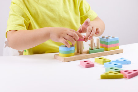 The child plays with colorful toy blocks. eco wooden toys. Little smart child playing natural toys. games for early development. Toy in childrens hands close-up. selective focusの写真素材