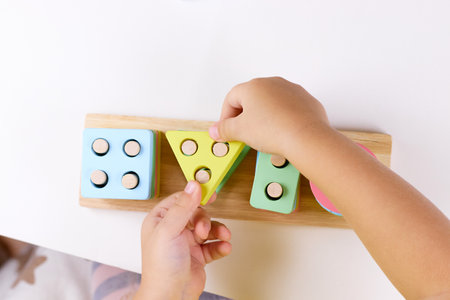The child plays with colorful toy blocks. eco wooden toys. Little smart child playing natural toys. games for early development. Toy in childrens hands close-up. selective focus. top viewの写真素材