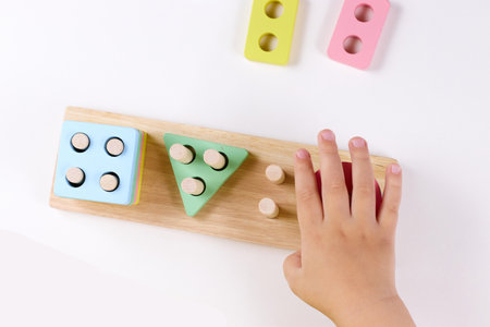 The child plays with colorful toy blocks. eco wooden toys. Little smart child playing natural toys....