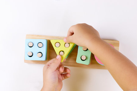 The child plays with colorful toy blocks. eco wooden toys. Little smart child playing natural toys. games for early development. Toy in childrens hands close-up. selective focus. top viewの写真素材