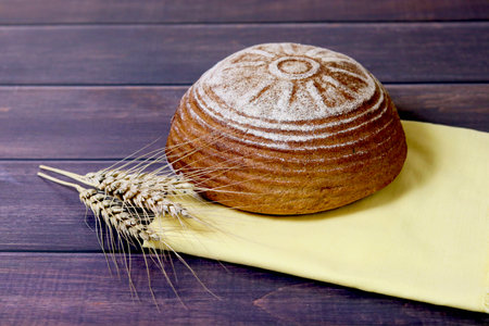 Freshly baked bread and ears of rye lie on a wooden board. Harvestの写真素材