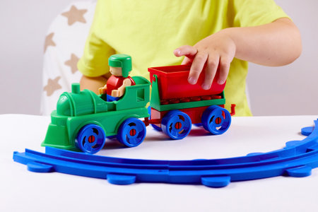 A small child plays with a train and a railroad. Games at home or kindergartenの写真素材