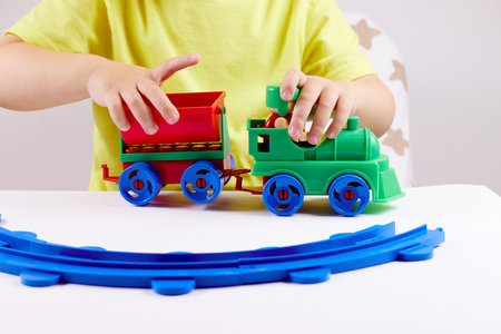 A small child plays with a train and a railroad. Games at home or kindergartenの写真素材