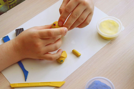 The child plays and builds figures from the play dough. Children's hands with colored plastic. Development of fine motor skills of fingers in childrenの写真素材