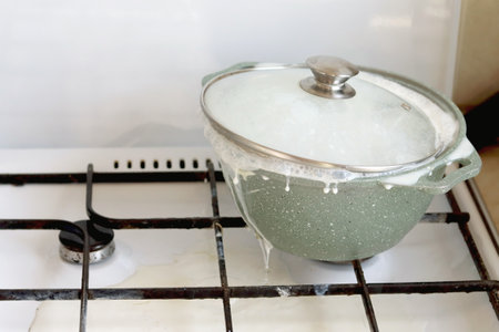 The porridge flows out of the pot. A saucepan on the stove with porridge flowing out.の写真素材