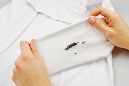 A woman holds dirty clothes in her hands. White clothes with stains. high quality photoの写真素材