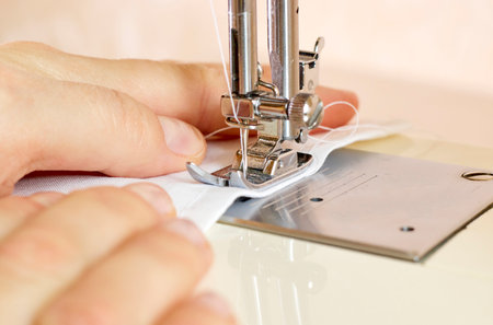 The process of tailoring clothes on a sewing machine. A woman sews at a sewing machine at workの写真素材