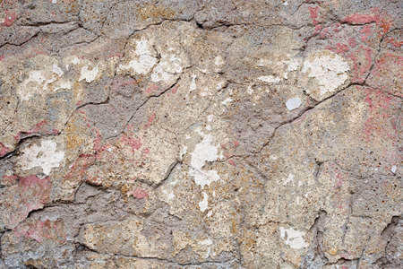 Fragment of an old weathered stone wall with cracks and chips. Partially chipped plasterの写真素材